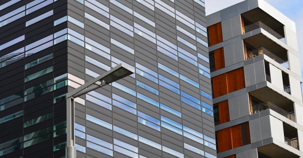 Low angle view of a modern glass office building and residential structure in daylight.