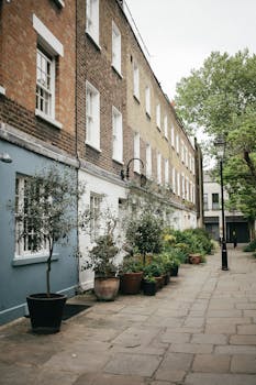 Quiet street in London with brick homes, potted plants, and cobblestone path.