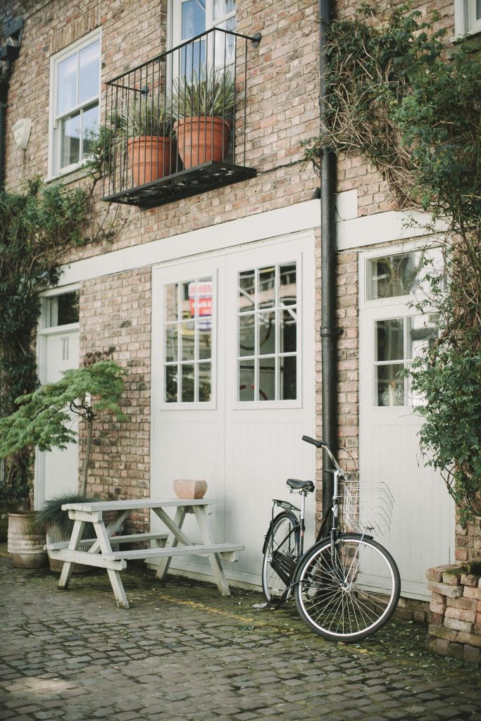 Quaint brick building exterior in London with bicycle and potted plants.
